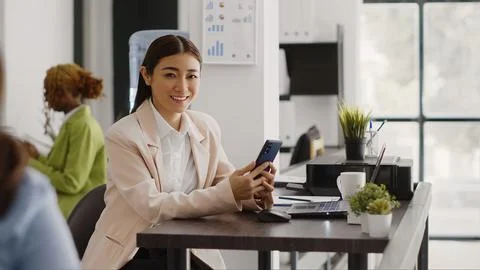 Asian office worker using smartphone app in workplace Stock Photos