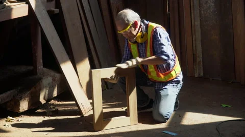 Asian old carpenter man using sandpaper on a piece of wood for furniture in w Stock Footage 158424209