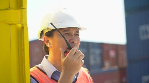 Asian old foreman talking on the walkie-talkie control loading Containers b.. Stock Footage 241724559