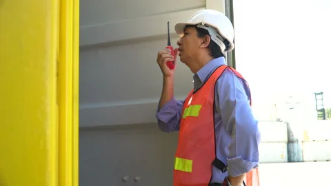 Asian old foreman talking on the walkie-talkie open and checking in  Contai.. Stock Footage 241724667