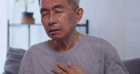 Asian old man having difficulty breathing while sitting on the sofa at home. Stock Footage 248406206