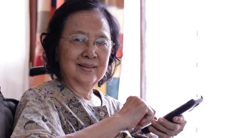 Asian old woman using a smart phone Stock Footage 128949676