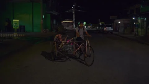 Asian pedicab driver transporting a tired passenger at night 库存影片 334376902