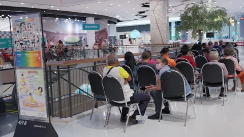 Asian People Sit &amp; Wait For Indoor Covid Flu Indoor Vaccination Clinic To Open Stock Footage 256055873