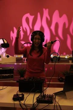 Asian performer having fun while playing eletronic music using professional Stock Photos