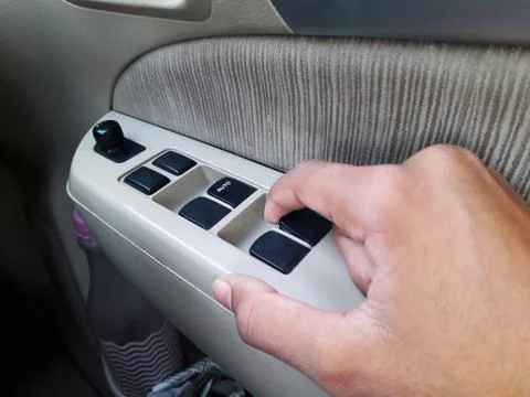An Asian person is pulling button to close side window glass of car Stock Photos