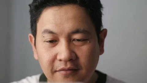 Asian person smiling while typing on his phone, man chatting on smart phone Stock Footage 231389324