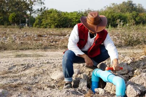 Asian plumber is checking blue pipe of water supply in garden. Stock Photos