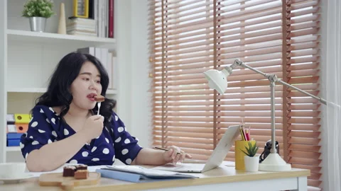 Asian plus-size office worker eating on her desk while working unhygienic food Stock Footage 158399822