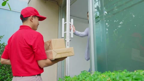 Asian Postman delivering package of goods to Young Asian cute girl customer. Stock Footage 164939142