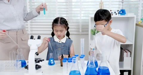Asian primary students conducting science experiment in classroom by mixing Video stock 336308539