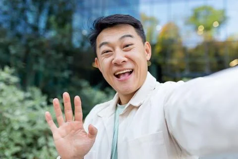 Asian programmer talking on video call using app on phone, view camera man Stock-Fotos