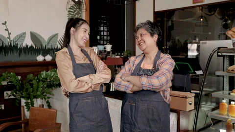 Asian retired single mother and daughter arm crossed in front of coffee mac.. Stock Footage 249303353
