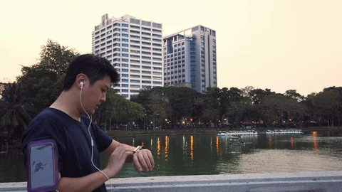 Asian runner run in park and look at smartwatch during sunset Video stock 102944504