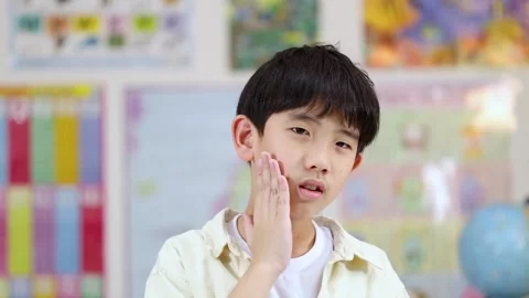 Asian School Boy Holding Cheek in Pain Due to Severe Toothache Stock Footage 324934474