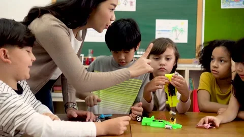 Asian school teacher assisting elementary students in science classroom Stock Footage