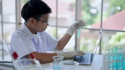 Asian scientist boy Analyzing liquid in tube with laptop computer Stock Footage 201361566