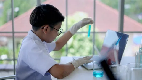 Asian scientist boy Analyzing liquid in tube with laptop computer Stock Footage 201361616