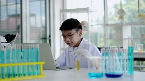Asian scientist boy Analyzing liquid in tube with laptop computer Stock Footage 201361724