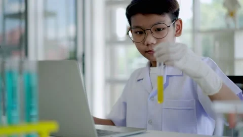 Asian scientist boy Analyzing liquid in tube with laptop computer Stock Footage 201361732