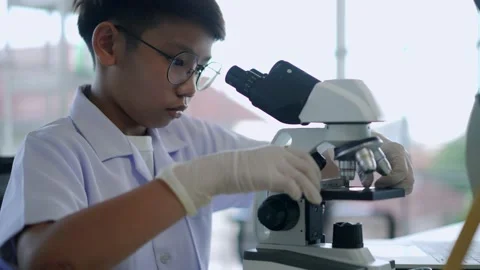 Asian scientist boy looking through microscope in laboratory Stock Footage 201362047