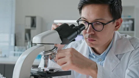 Asian Scientist Looking through Microscope in Laboratory Stock Footage 347049526