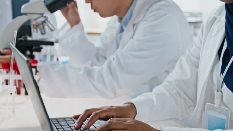 Asian Scientist Using Microscope with Colleagues in Laboratory Video stock 347054483