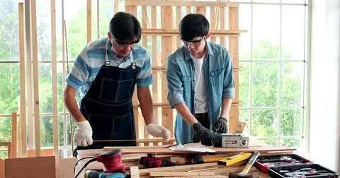 Asian senior carpenter teaching apprentice while working together in joinery 스톡 사진