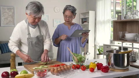  Asian senior couple is using a digital tablet, cooking together in kitchen. Stock Footage 221303219
