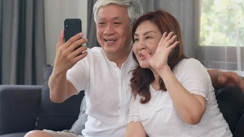 Asian senior couple using phone video call talking with family grandchild kids. Stock Footage 115122007