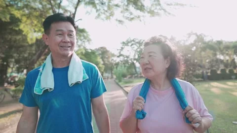 Asian senior couple walking together inside recreation public park happy smiling Stock Footage