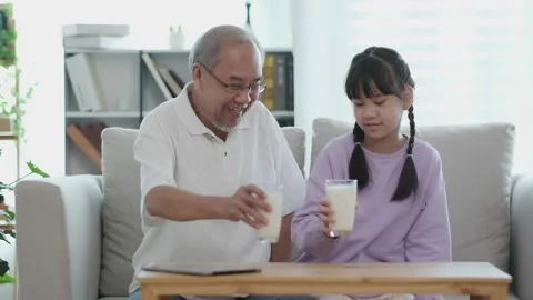 Asian Senior elder man and grandchild sit on sofa. Grandpa invites his grandd Stock Footage 153228487