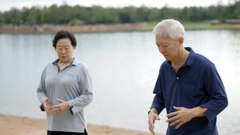 Asian Senior Elderly couple Practice Taichi, Qi Gong exercise next to the lak Stock Photos