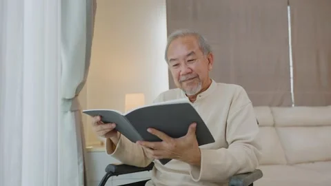 Asian Senior Elderly disabled man sit on wheelchair and reading book in hand Stock Footage 167853347