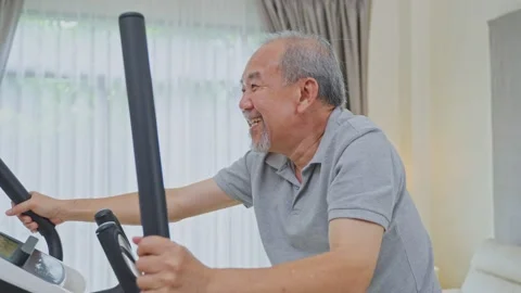 Asian senior elderly man use bike machine exercise at home for health Stock Footage 167844667