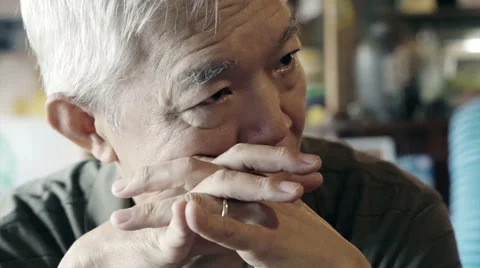 Asian senior guy with hand on face and thinking Stock Footage
