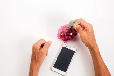 Asian senior inserting notes into a red piggy bank. Saving, retirement plan,  Foto stock