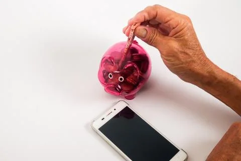 Asian senior inserting notes into a red piggy bank. Saving, retirement plan,  스톡 사진