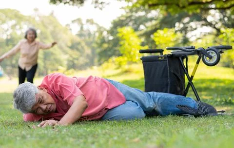 Asian senior man falling down from wheelchair on lying floor after trying pus Foto stock