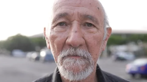 Asian senior man looking at camera with city street on background Stock Footage 276481081