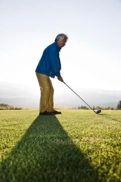 An asian senior man teeing up a golf ball and ready to swing. Stock Photos