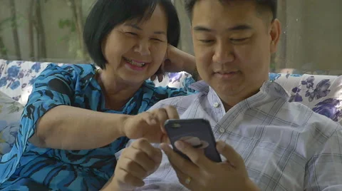Asian senior woman and Asian man using smart phone together, slow motion Stock Footage