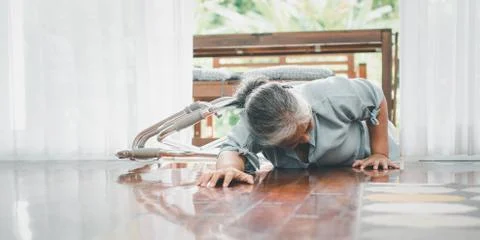 Asian senior woman falling down on lying floor at home after Stumbled at the  Stock Photos