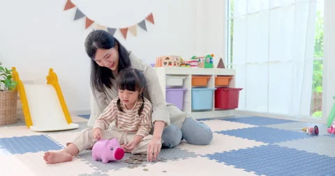 Asian single mother sits behind preschool daughter during money lesson at home, Stock Footage 339203375