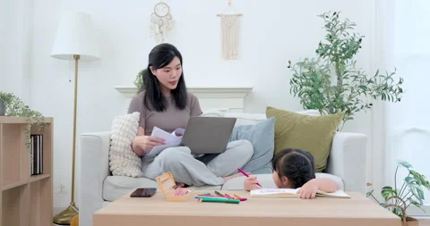 Asian single mother sitting on sofa with laptop and paper, watching preschool Stock Footage 334764147