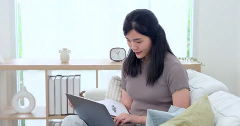 Asian single mother using laptop and study paper on sofa during preschool Stock Footage 332969373
