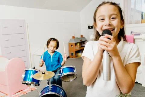 Asian sisters playing drums and singing Stock Photos