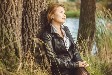 Asian sits alongside a tree 库存照片