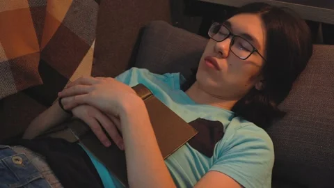 Asian Smart  Guy Is Sleeping at The Sofa With Book Stock Footage 148347555