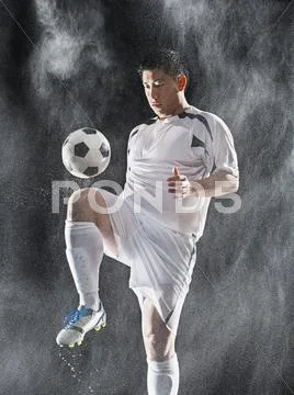 Asian Soccer Player Kicking Ball In Rain
